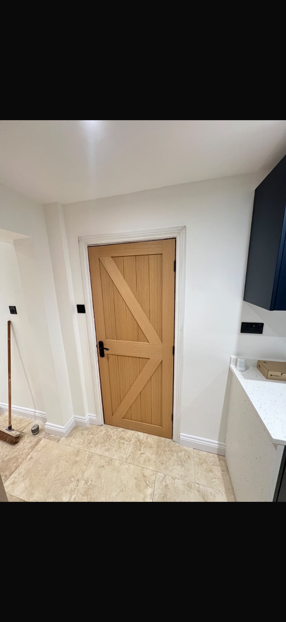 A timber door with diagonal bracing and a black handle.